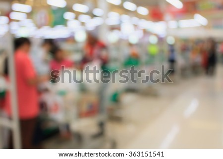 supermarket checkout payment terminal with customers blurred background