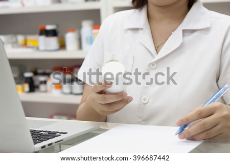 Pharmacist with laptop computer and medication in the pharmacy store