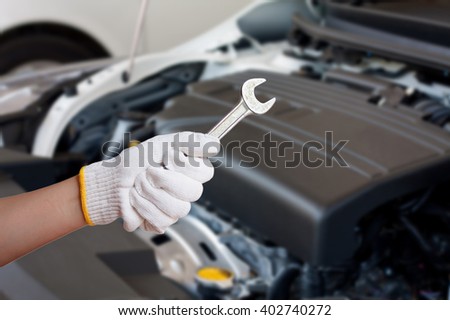 Hand of auto mechanic with wrench, car repair service centre