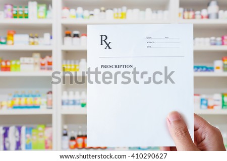 pharmacist hand holding prescription rx paper in hand over pharmacy store background