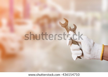 Mechanic holding pair of wrench at car servicing centre