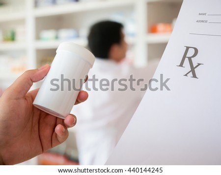 closeup hand of female pharmacist with prescription and medicine bottle at the pharmacy