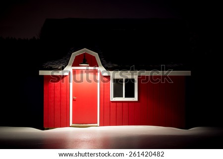 Small red barn with white trim during an icy winter night
