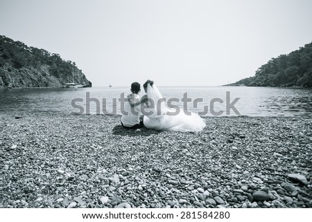 bride and groom sitting on the beach