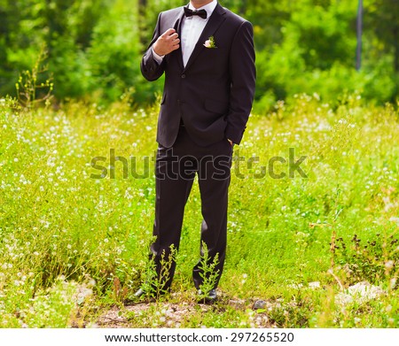 A groom putting on cuff-links as he gets dressed in formal wear .Groom\'s suit