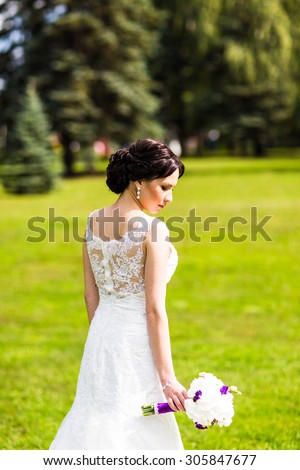 Beautiful bride in wedding dress and bridal bouquet, happy newlywed woman with wedding flowers, woman with wedding makeup and hairstyle. gorgeous young bride outdoors. Bride waiting for groom. bride