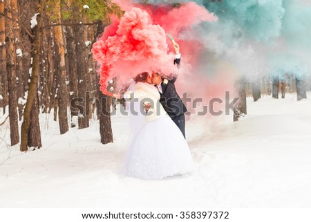 Wedding couple with color smoke in the winter park. Colour bomb