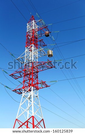 Electricity pylon and cables on blue sky background. Metal construction painted with red and white colors