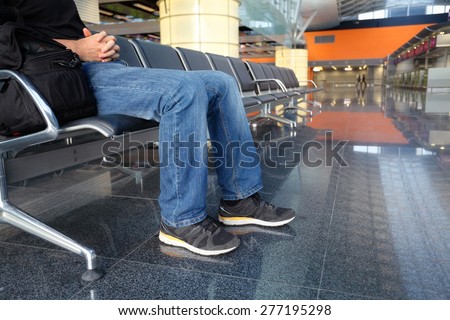 man in airport lounge sitting on chair and waiting for a plane