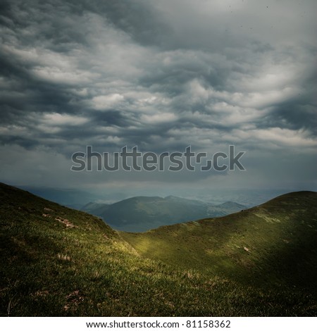 storm clouds over the mountains and small birds in a dark sky