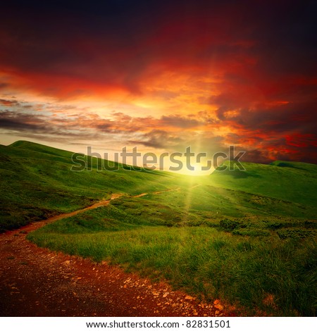 majestic sunset clouds and path through a mountain meadow to horizon
