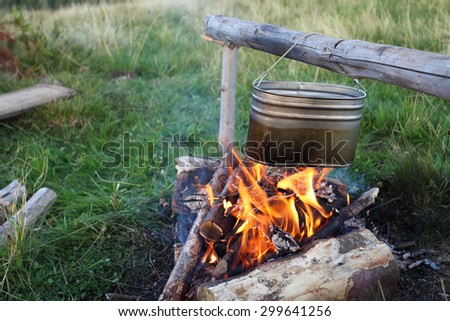 camp fire and preparing food in kettle