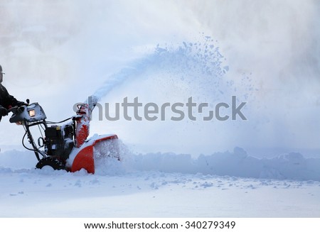 man working with snow blower after winter storm in city