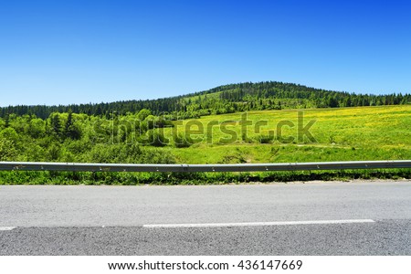 asphalt road and green hill with trees, summer landscape in mountains