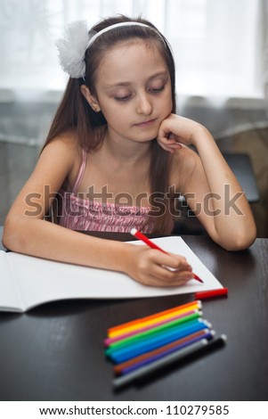 Cute little girl is drawing with felt-tip pen in school