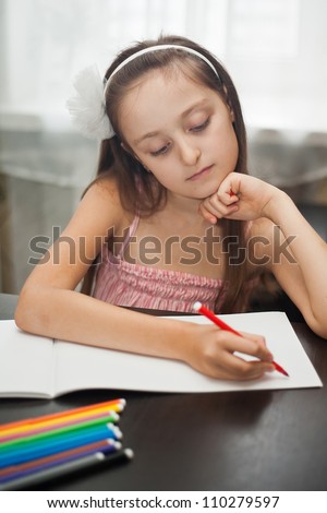 Cute little girl is drawing with felt-tip pen in school