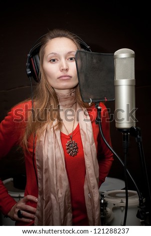 Female singer with headphones recording in studio