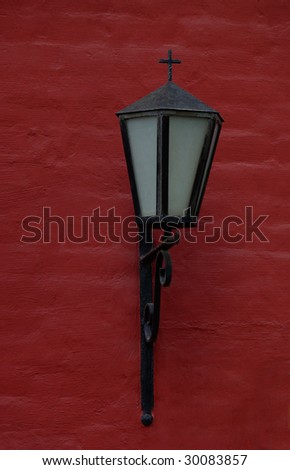 old black lantern with the cross on the dark red wall