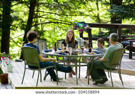 family eating dinner outdoors on a deck