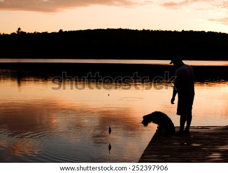 man and his dog fishing at sunset from a dock