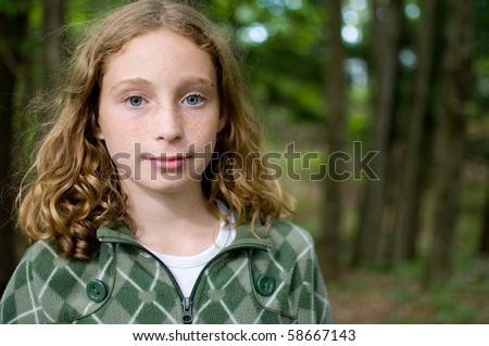 pretty blue eyed tween girl outdoors in a forest