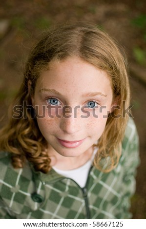 blue eyed tween girl looking up into the camera with a smile
