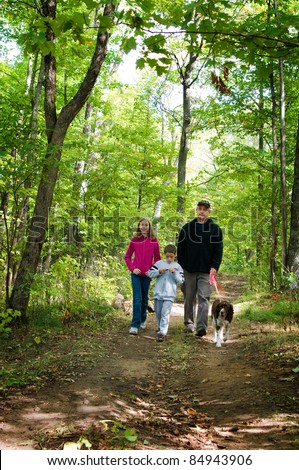 family walking their dog on a forest path