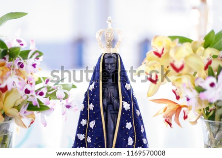 Statue of the image of Our Lady of Aparecida, mother of God in the Catholic religion, patroness of Brazil, decorated with flowers and orchids