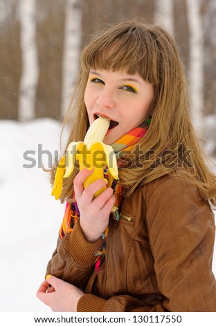 Smiling girl with color scarf biting a banana