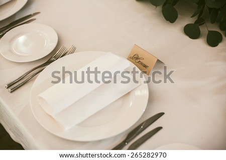 groom sign in russian on a wedding white table cloth with plate knife and forks