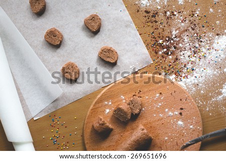 Cookie homemade preparation recipe step ingredients on wooden table flour, cocoa powder, dough pastry and sliced pastry ready to go on baking paper