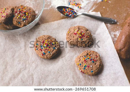Cookie homemade preparation recipe step ingredients on wooden table flour, cocoa powder, dough pastry and sliced pastry ready to go with ready fresh tasty sweet cookies on the side
