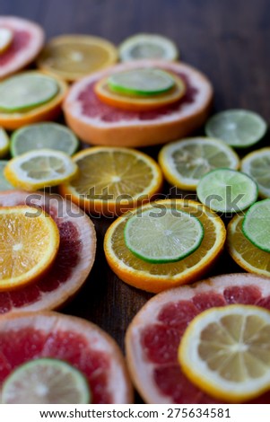 sliced citrus mix lemon grapefruit lime and orange in geometrical shapes on dark wood rustic background soft focus overhead-angle shot