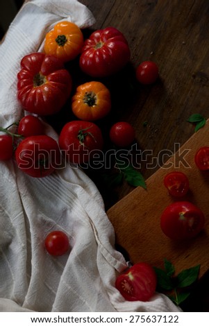 mix of fresh organic red yellow and cherry tomatoes with water drops from farmers market decorated in rustic style on a dark wood background soft focus overhead-angle shot