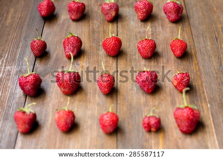 organic fresh sweet strawberries in rows as a seasonal breakfast in the morning right from farmers market on dark wood table background decorated in rustic style