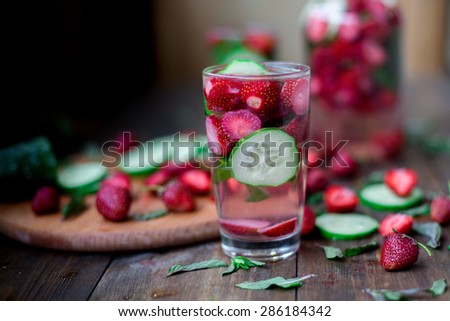 strawberry mint cucumber infused water decorated in rustic style on dark wood table background