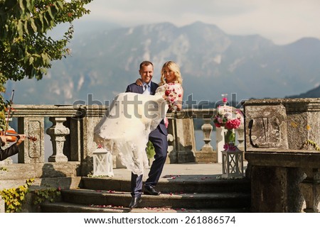 happy bride, groom carries the bride for hands