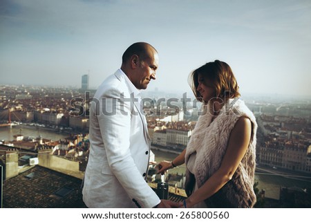 wonderful rich bride and groom look at each other on the terrace on the background of blue sky Lyon city