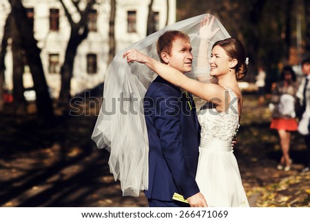 Happy bride is covering her groom with long veil