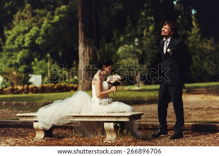 stylish charming rich bride sitting on a bench near stands groom in the park rome Italy sunny weather