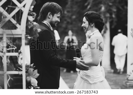 wonderful stylish rich happy bride and groom at a wedding ceremony look at each other in green garden near white arch with flowers Rome Italy  black and white