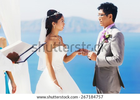 stylish rich smiling asian bride and groom  wedding look at each holding hands other in island Santorini greece sunshine