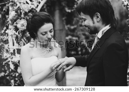 rich stylish happy bride and groom puts ring near a white wedding arch decorated with flowers peonies Rome Italy black and white