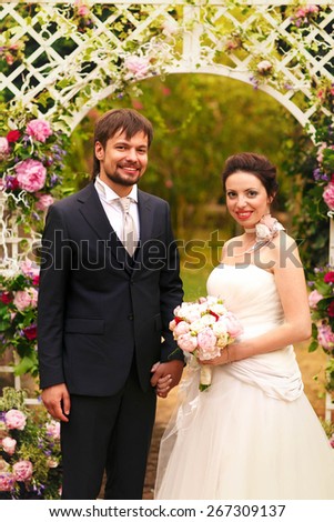 rich stylish happy bride and groom smiling near a white wedding arch decorated with flowers peonies Rome Italy