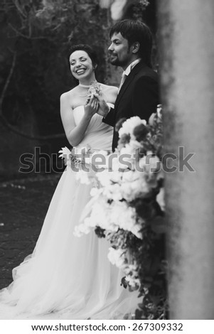 rich stylish happy bride and groom smiling near a white wedding arch decorated with flowers peonies Rome Italy black and white