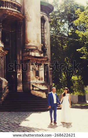 bald groom and bride brunette walk near church on the streets of the old city Lviv Ukraine