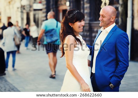brunette bride hugging at the bald groom on the streets of the old city of Lviv Ukraine