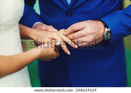Groom putting a wedding ring on bride\'s finger