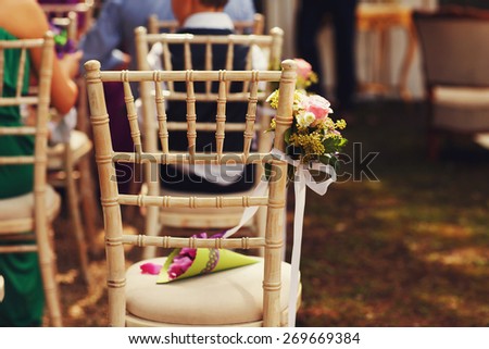 wooden wedding chair decorated with flowers ribbons tipes