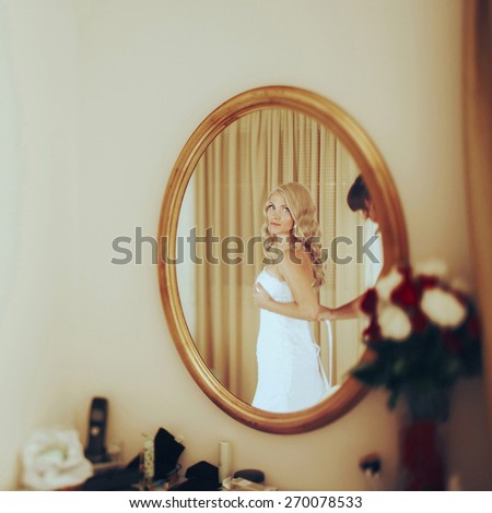blonde sexy bride clothe wedding dress in fron of elipse mirror